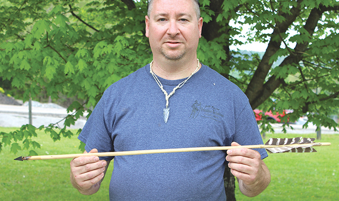 Jeff Payne showcases an arrow he crafted and wears a glass arrow point, which he knapped, around his neck.  KENNETH CROWSON PHOTO